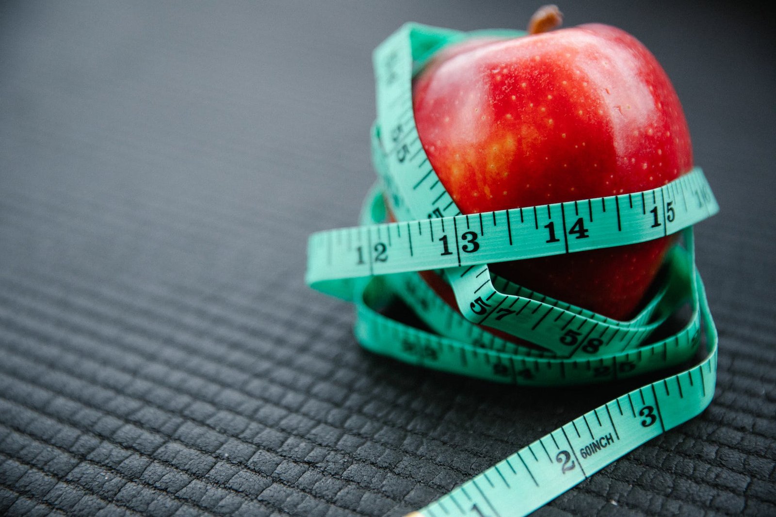 measuring tape wrapped around red apple